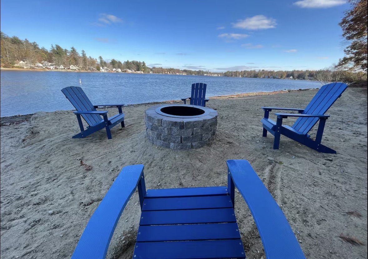 Blue Adirondack chairs and a firepit on the lake shore